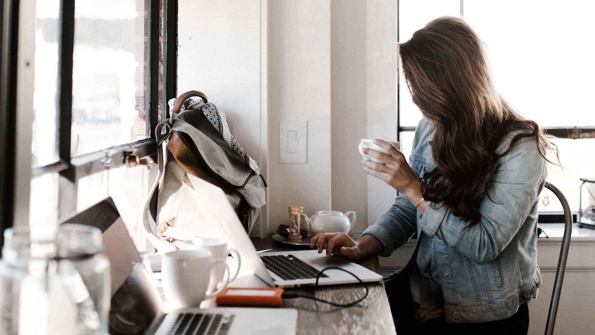 Woman drinking coffee and working on her laptop